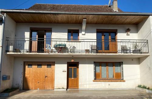 a white house with wooden doors and a balcony at Chez Doukine, Appartement avec balcon à Chouzelot in Chouzelot