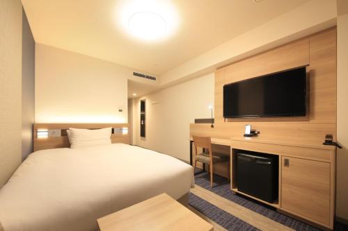 a hotel room with a bed and a flat screen tv at Richmond Hotel Tenjin Nishi-Dori in Fukuoka