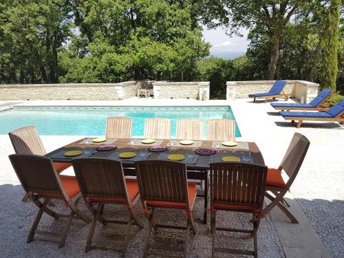 un tavolo da pranzo e sedie accanto alla piscina di Villa Provence élégante climatisée a Oppède