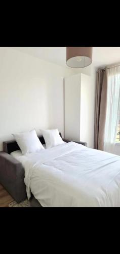 une chambre avec un lit avec des draps blancs et une fenêtre dans l'établissement Appartement cosy à Saint-Denis, 35 m², pour 4 personnes, à Saint-Denis