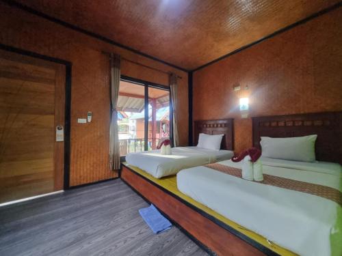 a room with two beds and a door with a window at Sunny House Garden in Phra Ae beach