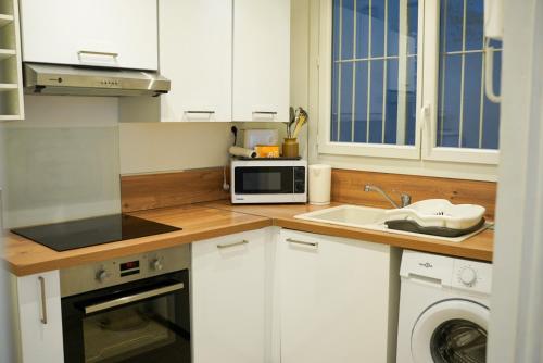 a white kitchen with a sink and a microwave at Somptueux Studio Hyper centre Perpignan in Perpignan