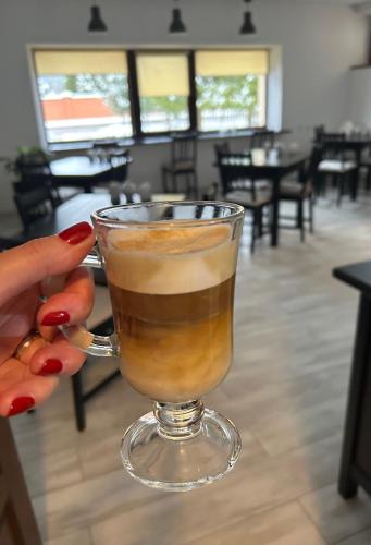 a woman holding a glass of coffee in a restaurant at Villa Kmeller in Lviv