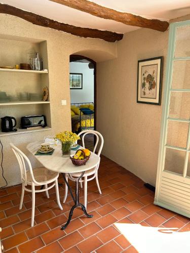 a dining room with a table and chairs and a kitchen at Aux Deux Fontaines - Au coeur de la Provence in Vaugines