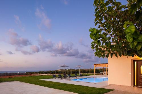 a pool with chairs and umbrellas in a yard at Villa Red Sunset by Estia in Sfakaki