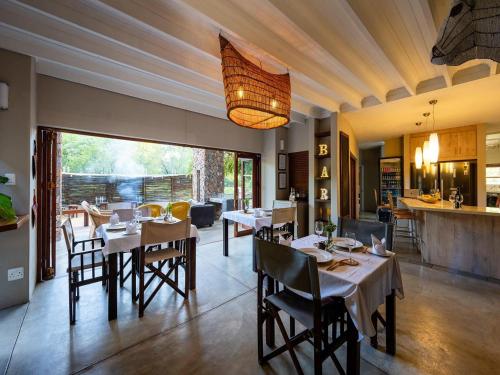 a dining room with tables and chairs and a kitchen at eKhaya Bush Lodge in Hoedspruit