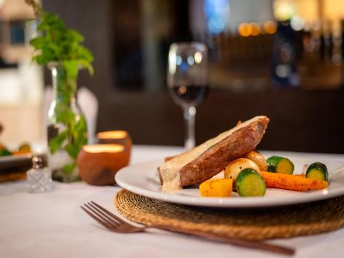 a plate of food on a table with a glass of wine at eKhaya Bush Lodge in Hoedspruit