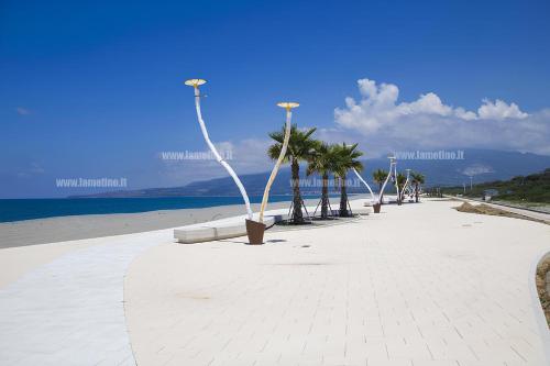 a beach with palm trees and street lights on it at Stylish Apt TERINA - Le Lincelle, Lamezia - bright, spacious, elegant and with terrace in SantʼEufemia Lamezia