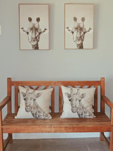 a wooden bench with two giraffe heads on it at The Wild Olive Sanctuary Accommodation in Paterson
