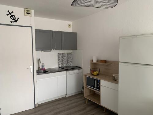 Elle comprend une petite cuisine avec des placards blancs et un réfrigérateur. dans l'établissement Sol-y-Days Floralies, grand duplex 6 personnes proche des plages, au Grau-du-Roi