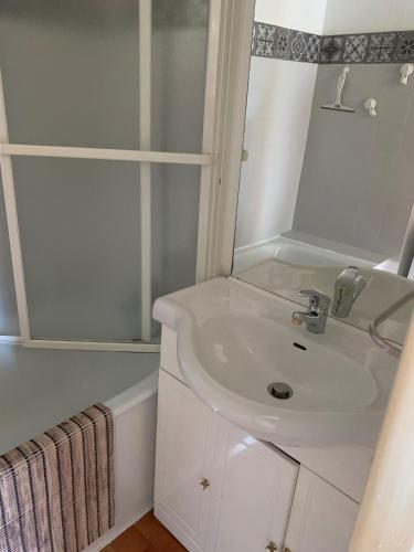 une salle de bain blanche avec un lavabo et un miroir dans l'établissement Sol-y-Days Floralies, grand duplex 6 personnes proche des plages, au Grau-du-Roi