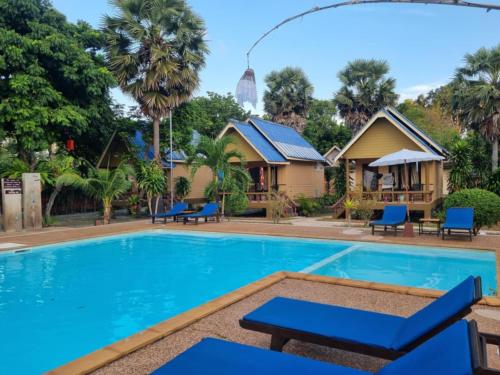 a pool at a resort with blue chairs and trees at Sunny House Garden in Phra Ae beach
