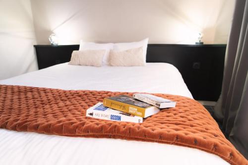 a couple of beds with books on the bed at Hôtel du Beffroi Gravelines Dunkerque in Gravelines