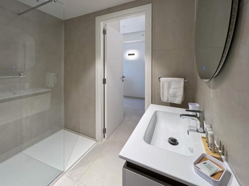 a white bathroom with a sink and a mirror at Mercury Suite Bright w Pool access by Arco Collection in St. Julianʼs
