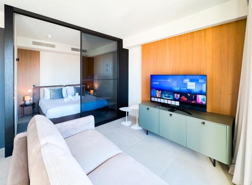 a living room with a couch and a flat screen tv at Mercury Suite Bright w Pool access by Arco Collection in St. Julianʼs