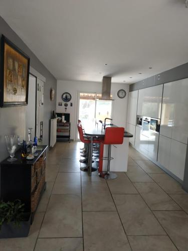 Il dispose d'une cuisine et d'un salon avec une table et des chaises rouges. dans l'établissement Welcome to La Maison du bonheur, à Vidauban