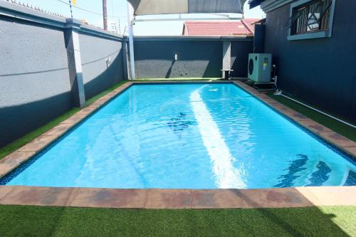 a large blue swimming pool on the side of a house at KwaZikode Guesthouse in Meyerton