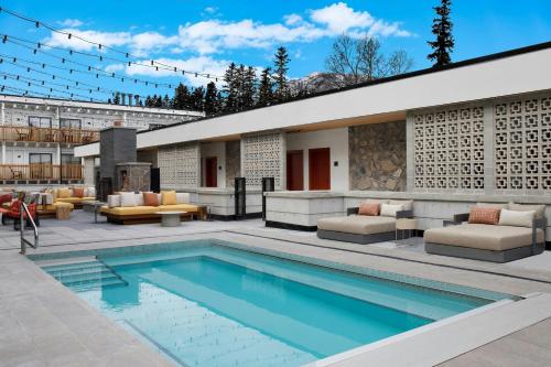 a swimming pool with furniture and a building at Moxy Banff in Banff