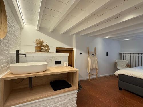 a bathroom with a white sink and a bed at Hoeve Gensters in Oudenaarde