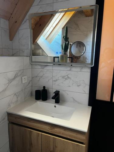 a bathroom with a white sink and a mirror at Grange Des Rêves in Lichtenberg