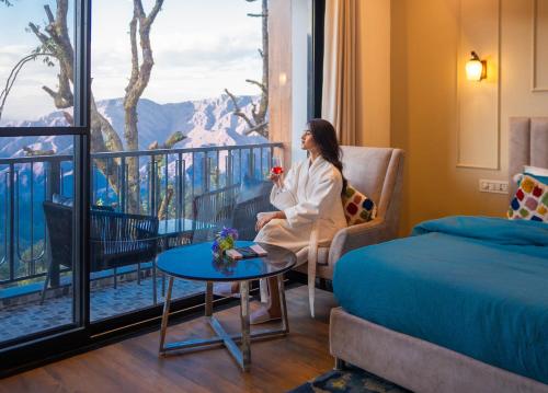 a woman sitting in a chair in a room with a window at Perfectstayz Premium Westend at Mall Road in Mussoorie