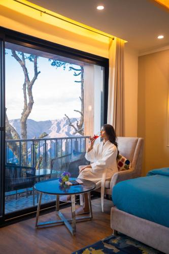 a woman sitting on a couch in a room with a window at Perfectstayz Premium Westend at Mall Road in Mussoorie