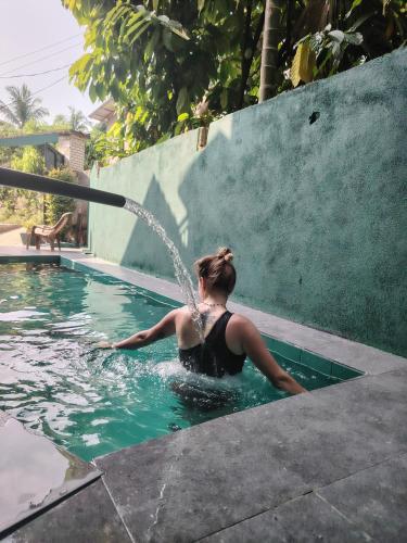a woman in a pool with a water hose at Nice View Safari villa in Udawalawe