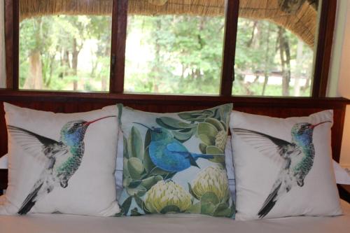 two birds on pillows on a bed in front of a window at House On Blyde in Kampersrus AH