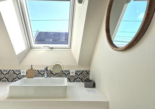 une salle de bain avec un lavabo blanc et un miroir dans l'établissement Ty-Bod Les Gîtes de la Côte d'Amour, à Batz-sur-Mer