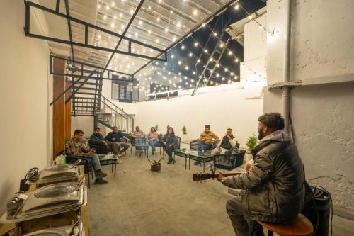 a group of people sitting in a room playing guitar at Perfectstayz Premium Westend at Mall Road in Mussoorie