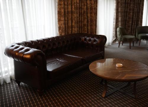 a brown leather couch in a living room with a table at Riva Ankara Hotel in Ankara