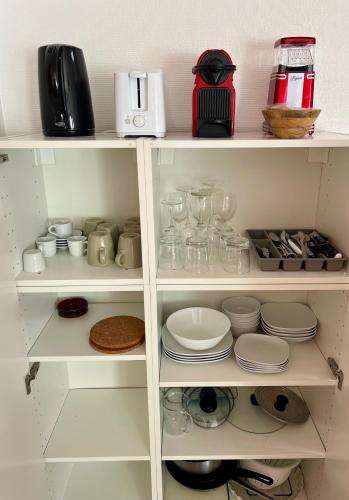 une armoire blanche remplie de vaisselle et d'appareils dans l'établissement Joli T2 47m2 au calme absolu, à 2 pas de la gare avec parking privé, à Saint-Cyr-lʼÉcole