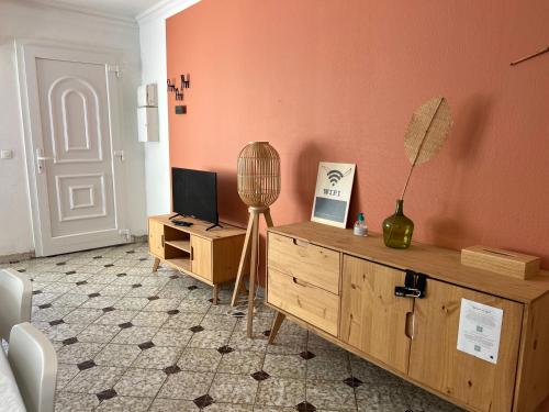 a living room with a television and a wooden dresser at Joli T2 47m2 au calme absolu, à 2 pas de la gare avec parking privé in Saint-Cyr-lʼÉcole