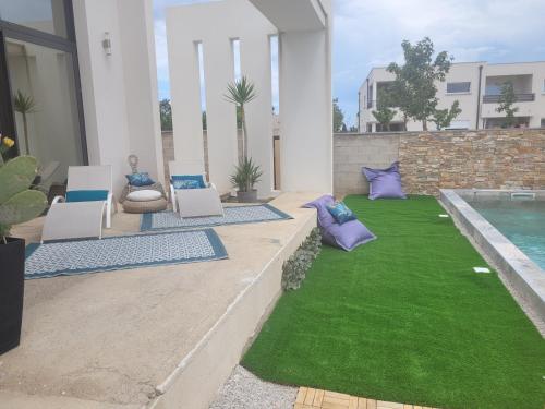 une cour avec une pelouse, des chaises et une piscine dans l'établissement Magnifique Villa piscine jacuzzi privé, à Saint-Féliu-dʼAvall