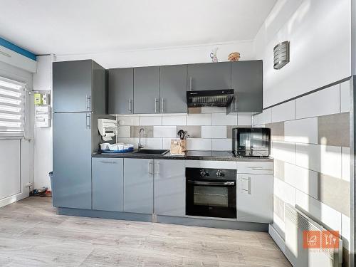 une cuisine équipée d'appareils en acier inoxydable et de placards gris dans l'établissement Le Cocon Marin, à Boulogne-sur-Mer