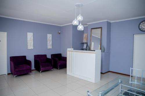 a waiting room with purple chairs and a mirror at Avenue Inn in Gaborone