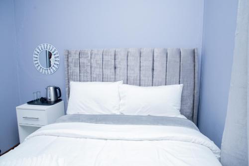 a bedroom with a white bed with a gray headboard at Avenue Inn in Gaborone