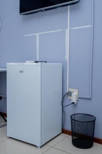 a white refrigerator in a room with a black trash can at Avenue Inn in Gaborone