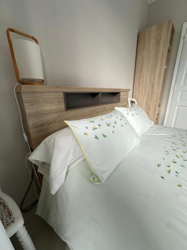 a white bed with a wooden headboard and white pillows at Chambres d'hôtes Le Bignon dans les Alpes Mancelles in Villaines-la-Juhel