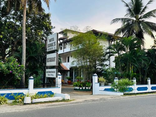 a sign in front of a house with palm trees at Hotel Sunil's in Kataragama
