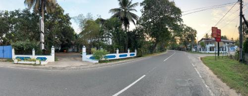 an empty street with a white and blue fence at Hotel Sunil's in Kataragama