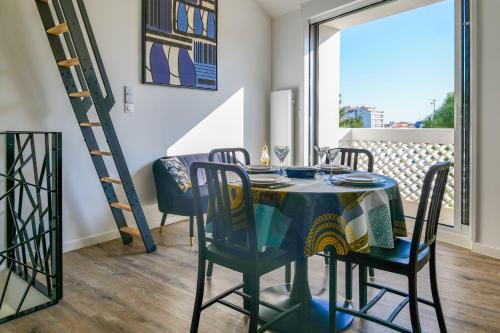 une salle à manger avec une table, des chaises et une échelle dans l'établissement maison entierement renovee face au chenal pour 4 pers - la chaume, à Les Sables-dʼOlonne
