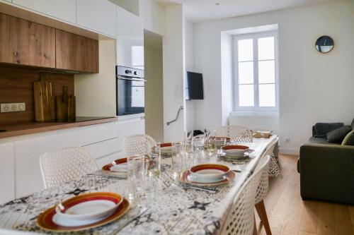 une salle à manger avec une table, des assiettes et des verres dans l'établissement Maison de pêcheur rénovée - 3 chambres et patio extérieur - 6 personnes, à Les Sables-dʼOlonne