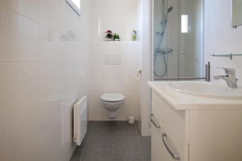 une salle de bain blanche avec des toilettes et un lavabo dans l'établissement superbe villa residence oasis park - 8 personnes - piscine chauffee, à Les Sables-dʼOlonne