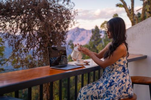 a woman sitting at a table with a laptop at Perfectstayz Premium Westend at Mall Road in Mussoorie