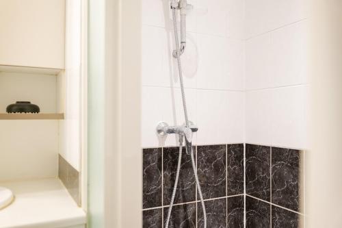 La salle de bains est pourvue d'une douche et d'un mur en carrelage noir. dans l'établissement Studio cosy idéalement situé - proche plage - 2 personnes, à Les Sables-dʼOlonne