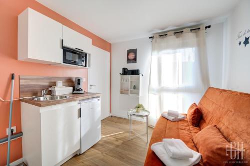 un salon avec un canapé orange et une cuisine dans l'établissement Jupiter - Proche A10 - 2V - Parking, à Saint-Pierre-des-Corps