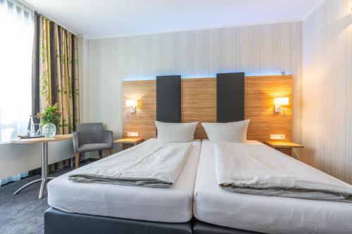 a bedroom with a large bed and a desk at Seehotel Forst in Forst
