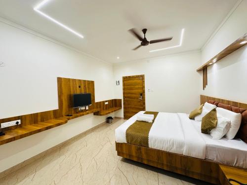 a bedroom with a bed and a flat screen tv at Shambhavi Hotel And Convention Centre in Udupi