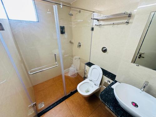 a bathroom with a shower and a toilet and a sink at Shambhavi Hotel And Convention Centre in Udupi